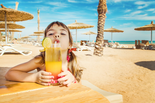 Kind am Strand mit Trinkglas